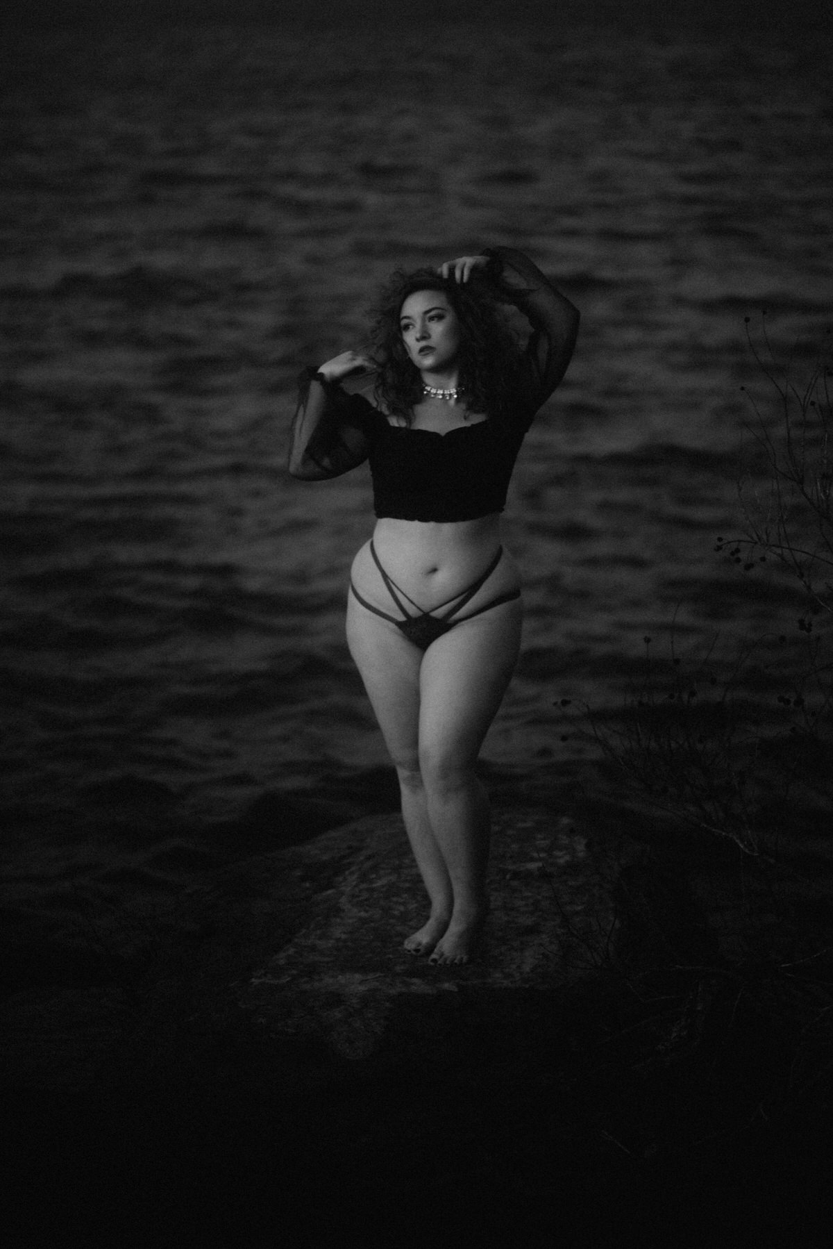 Black and white film boudoir photo on ocean rock