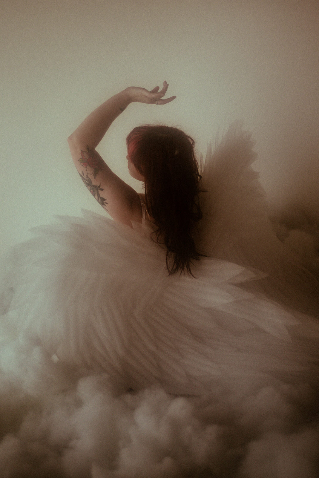 A woman posing with an arm above her head with angel wings in Dallas