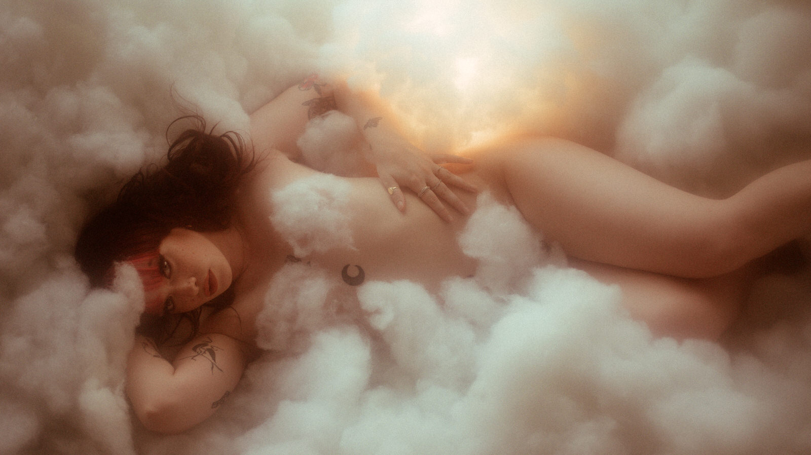 Woman posing nude in cloud photography set with lights