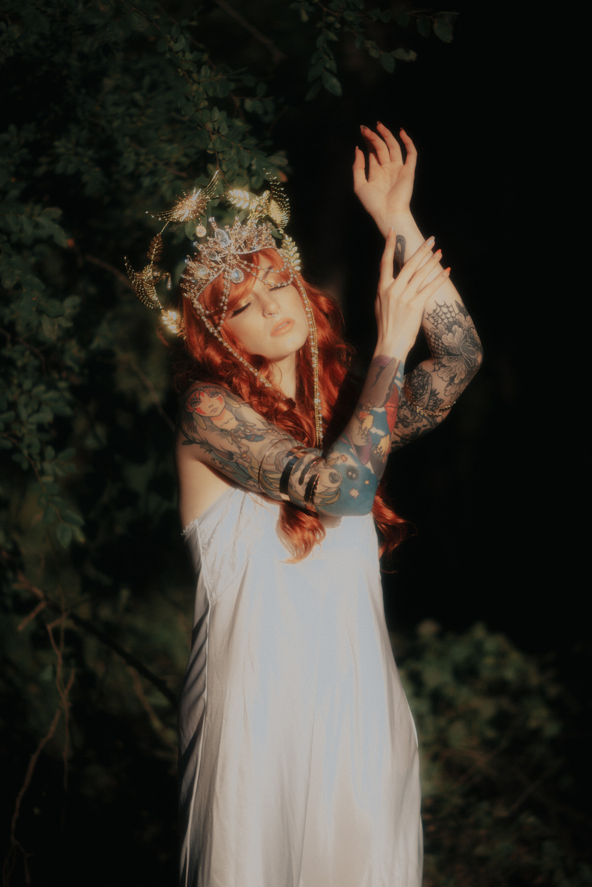 Beautiful model with tattoos and red hair wearing a white slip dress in the sunlight.