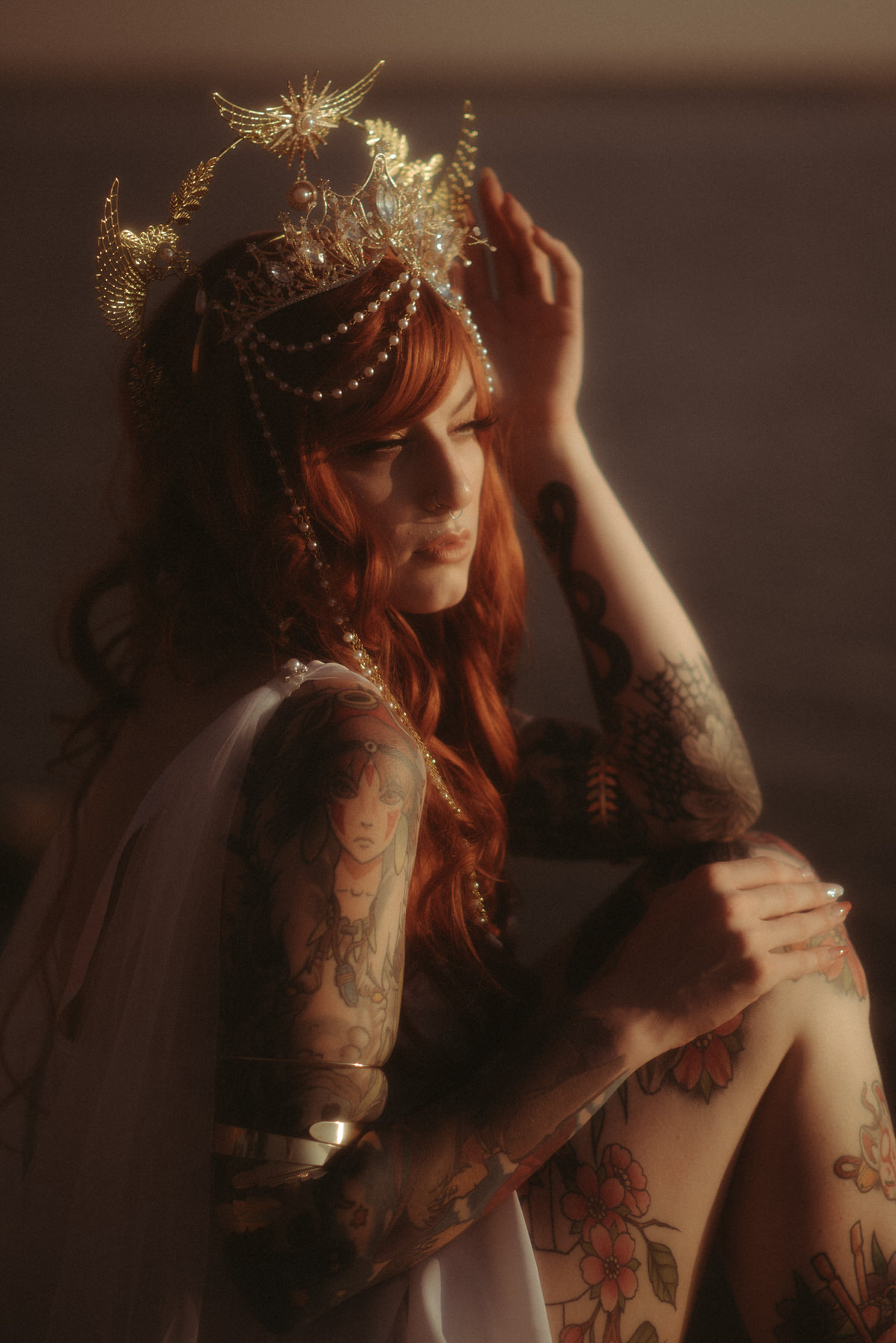Beautiful woman with tattoos with red hair wearing a gold crown.