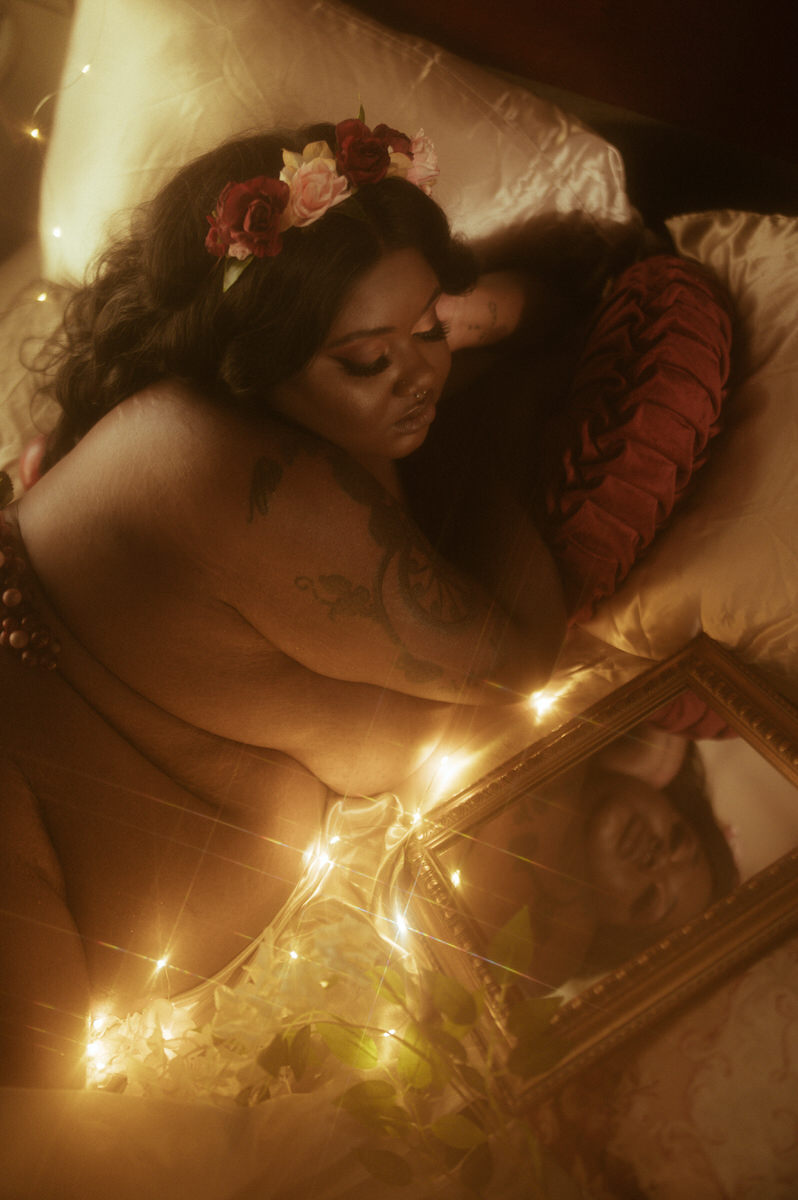 A woman laying on a bed with a mirror in front of her.