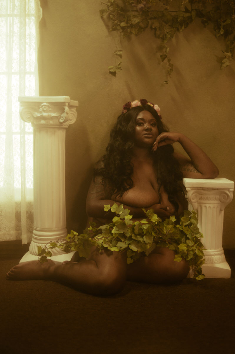 A woman sitting on the floor with ivy growing around her.