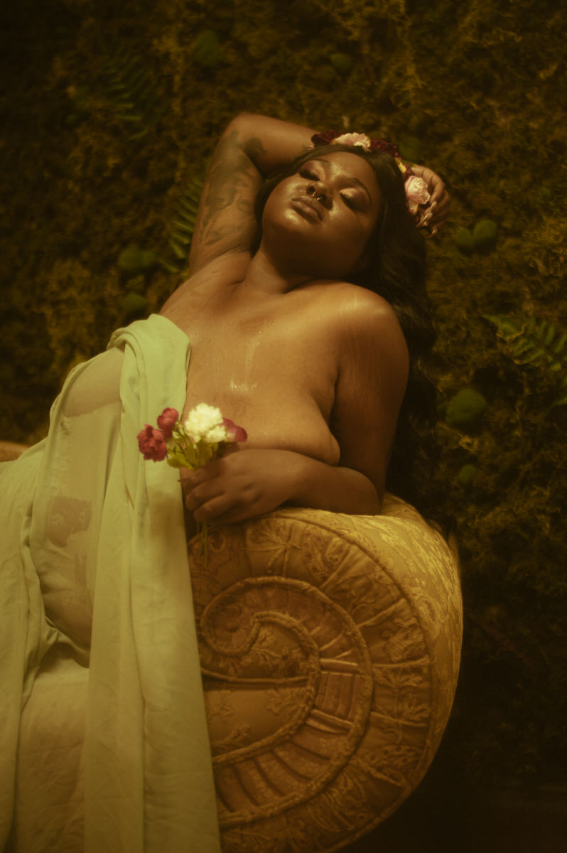 A woman laying on a couch with flowers in her hair.