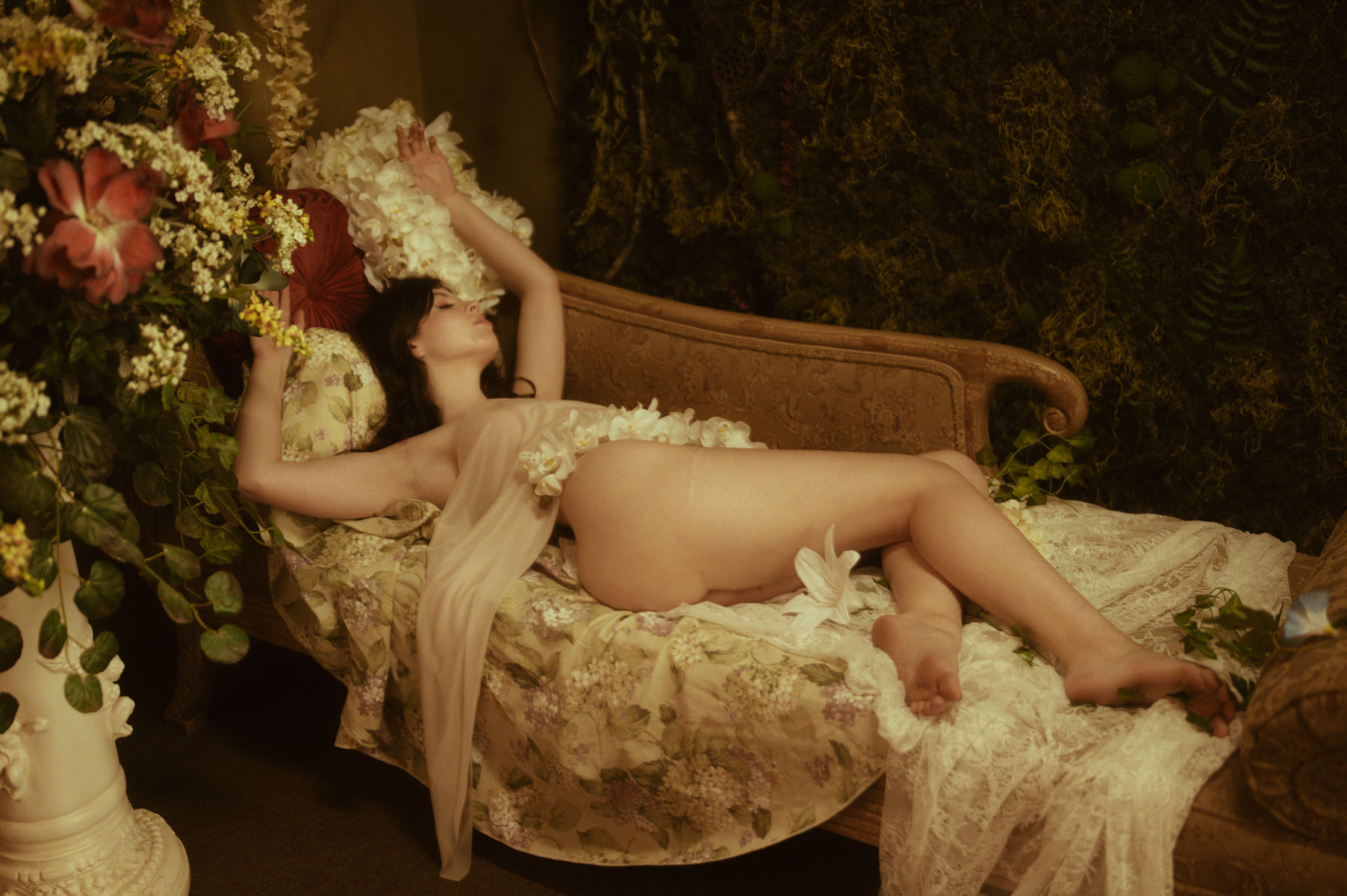 A woman posing for Dallas Boudoir Photography, surrounded by flowers on a couch.