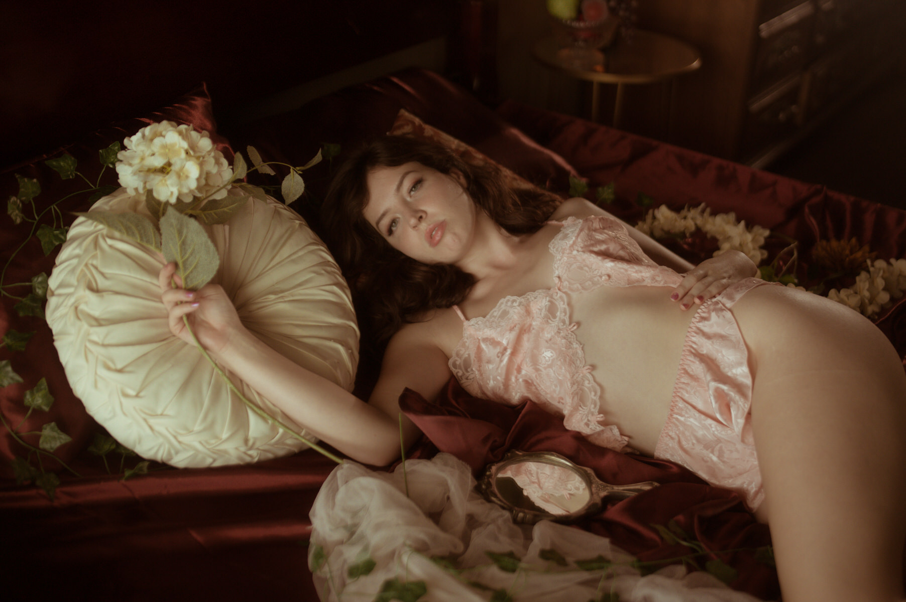 A woman posing on a bed with flowers for Dallas Boudoir Photography.