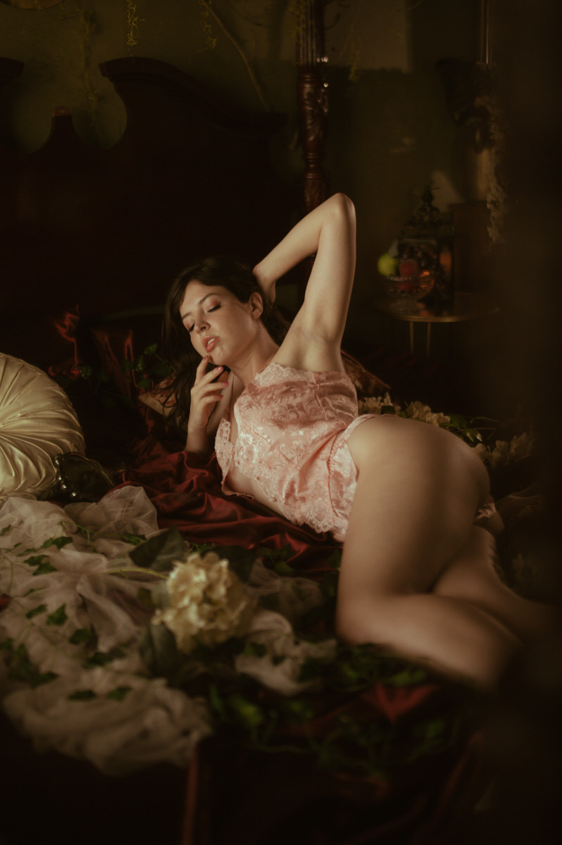 A woman in pink lingerie posing for Dallas Boudoir Photography on a bed.