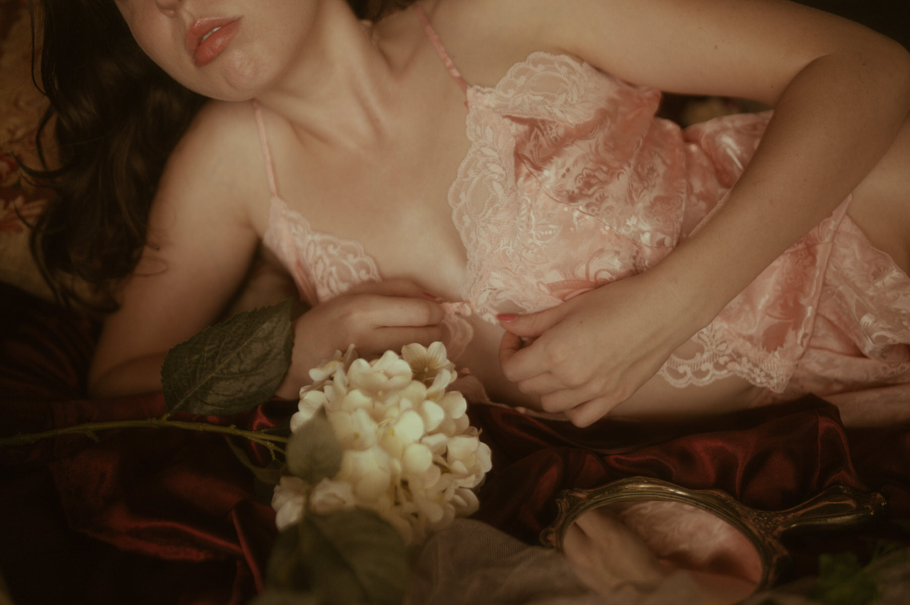 Dallas Boudoir Photography: Pink lingerie-clad woman on a bed surrounded by flowers.