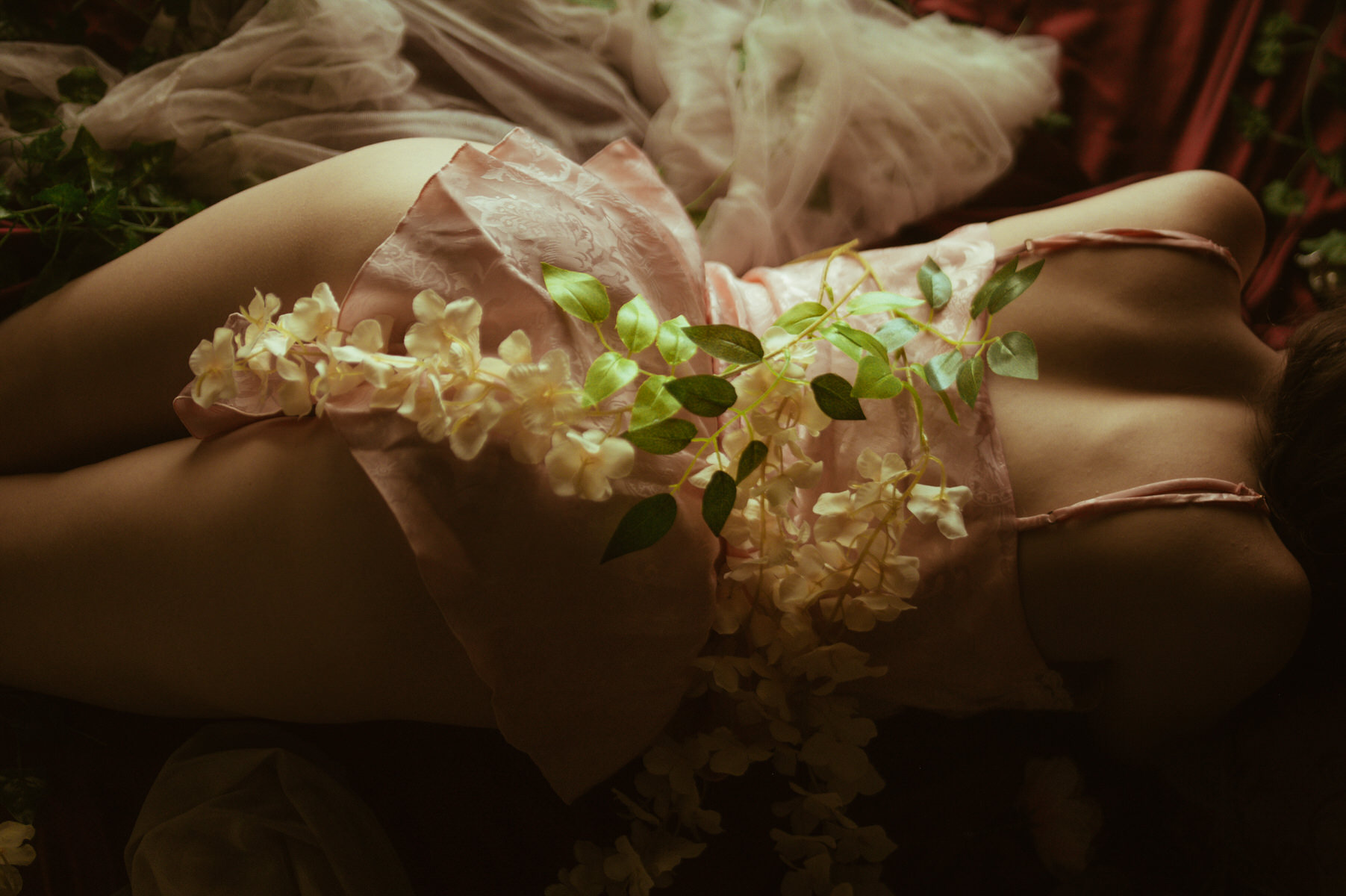 A woman posing on a bed adorned with flowers in Dallas Boudoir Photography.