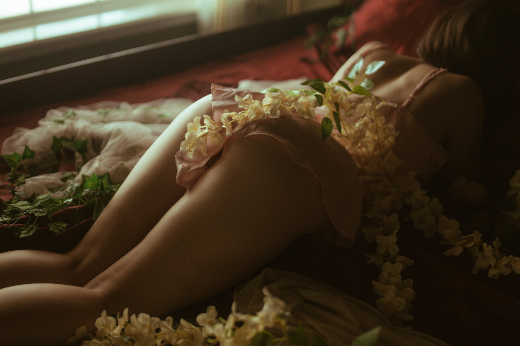 Dallas Boudoir Photography featuring a woman surrounded by flowers on a bed.