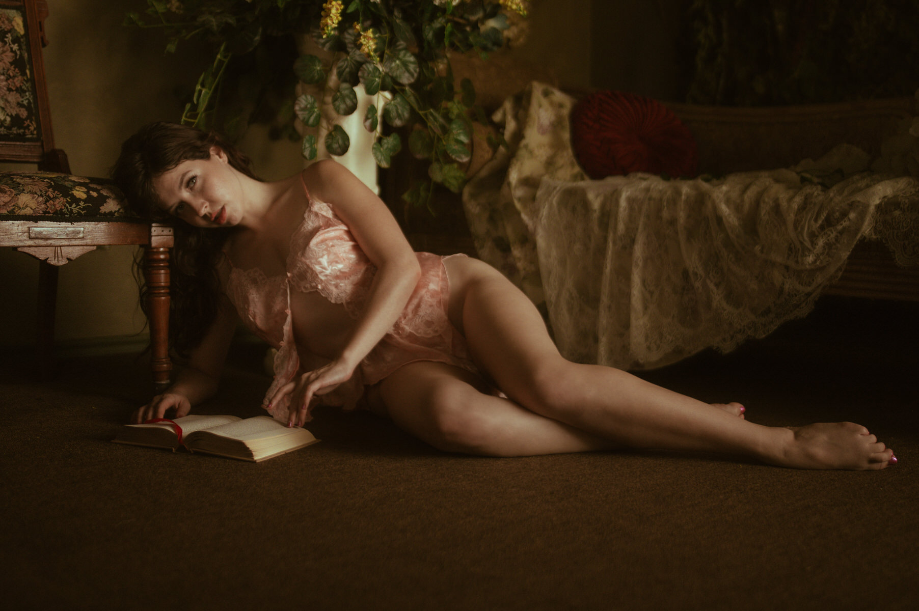 A woman engaged in Dallas Boudoir Photography, laying on the floor reading a book.