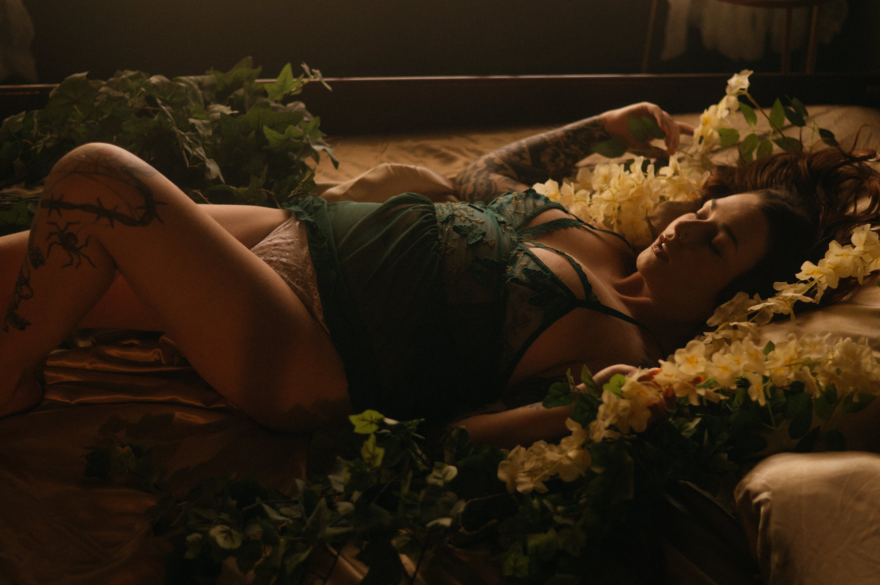 A woman, surrounded by a stunning array of flowers, gracefully poses on a bed in this captivating Dallas boudoir photography session.