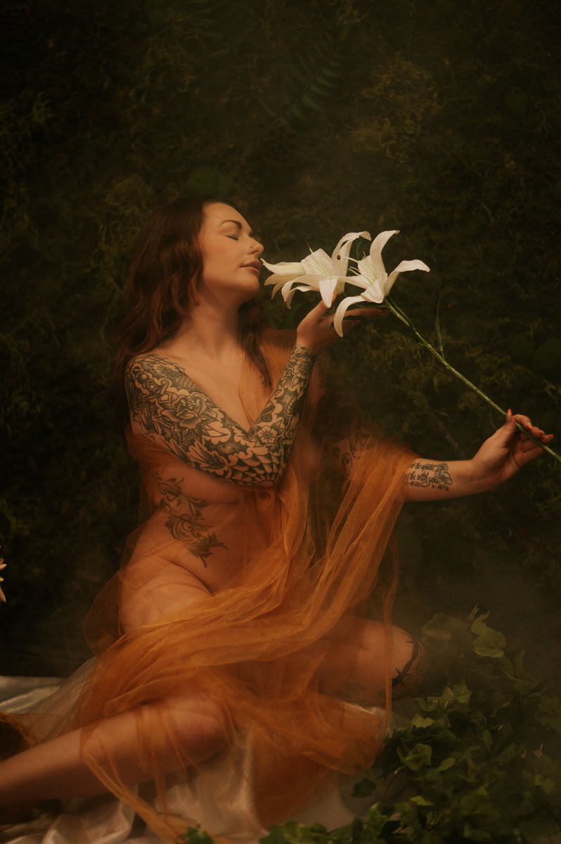 A woman covered by tulle s is holding a flower during a Dallas boudoir photoshoot.