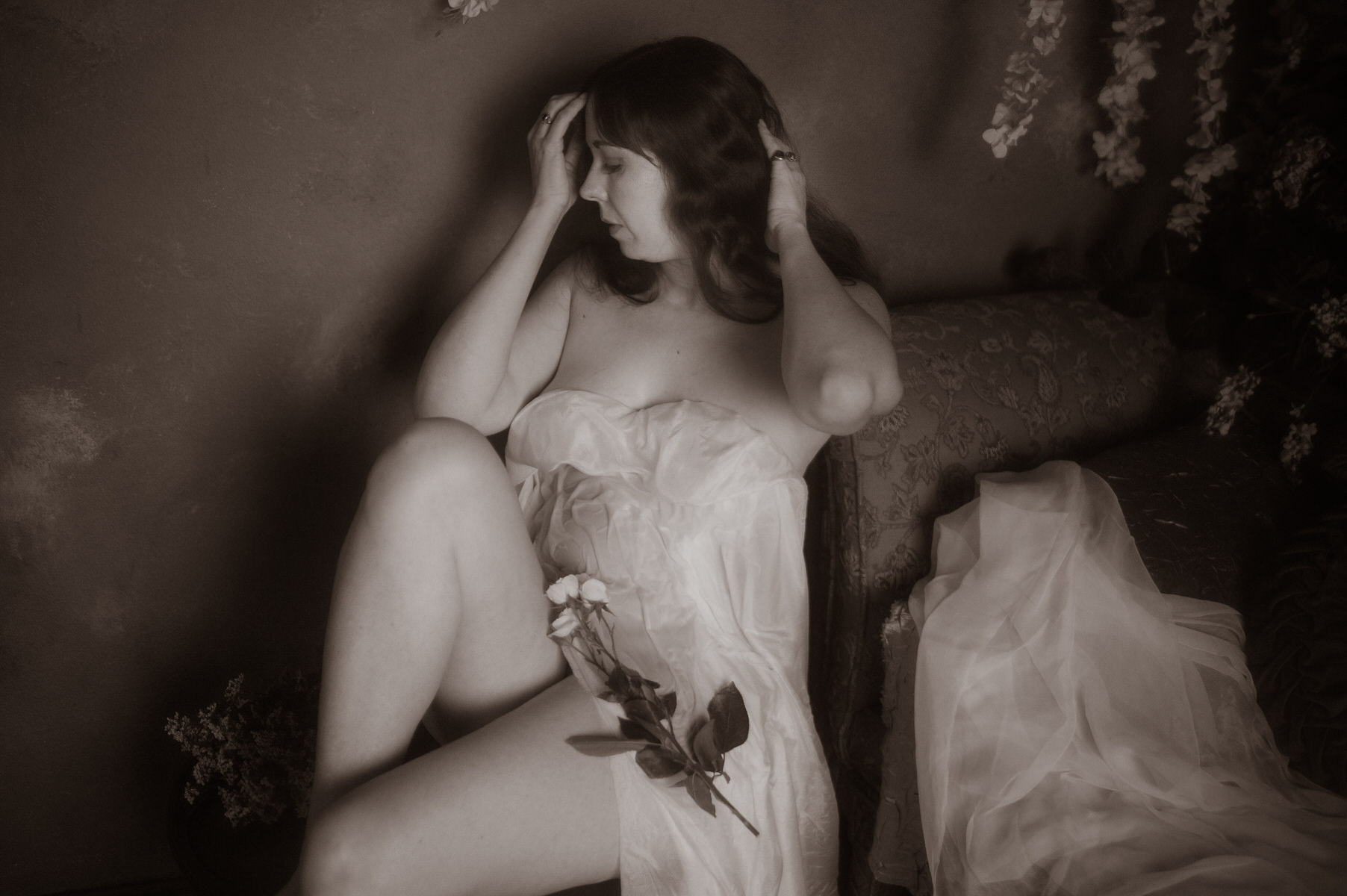 A woman wearing wet silky fabric for a painterly boudoir photography session.