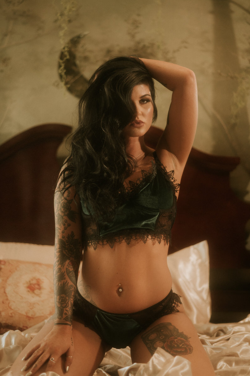 A woman with tattoos sitting on a bed, captured beautifully through Waco boudoir photography.