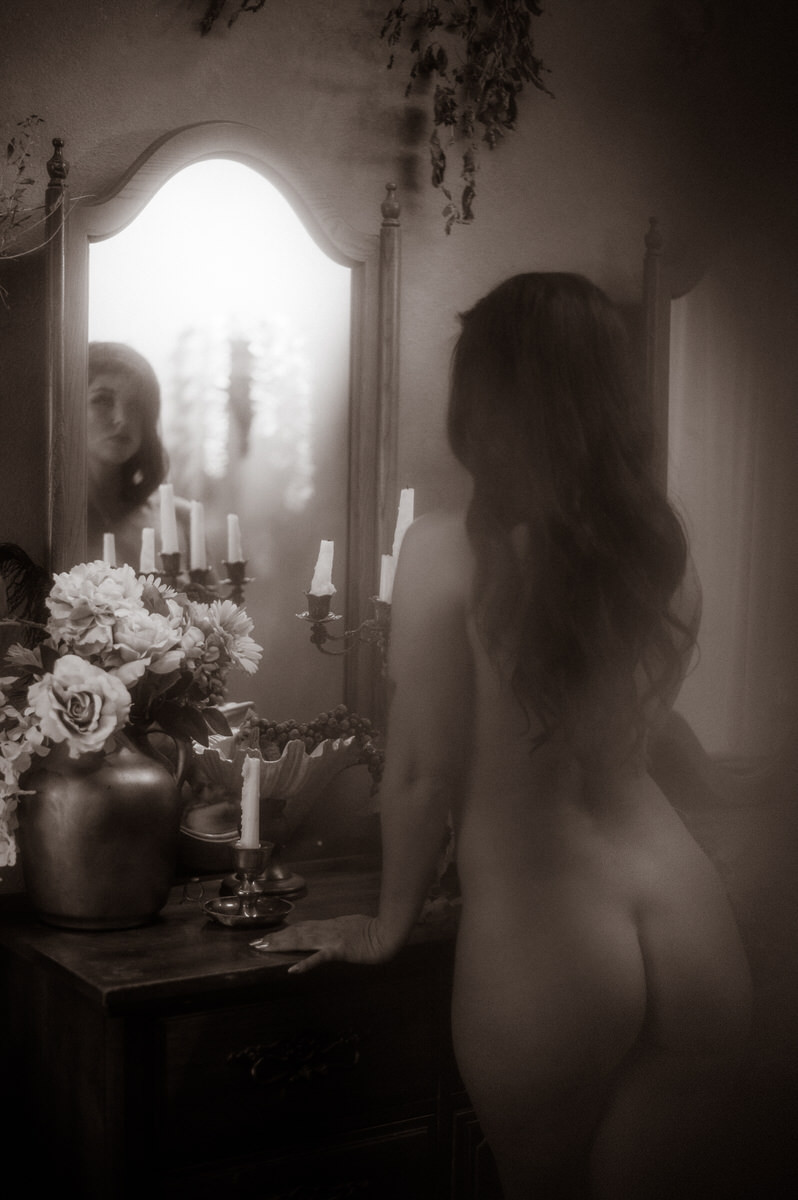 A nude woman standing in front of a mirror, captured beautifully through Dallas boudoir photography.