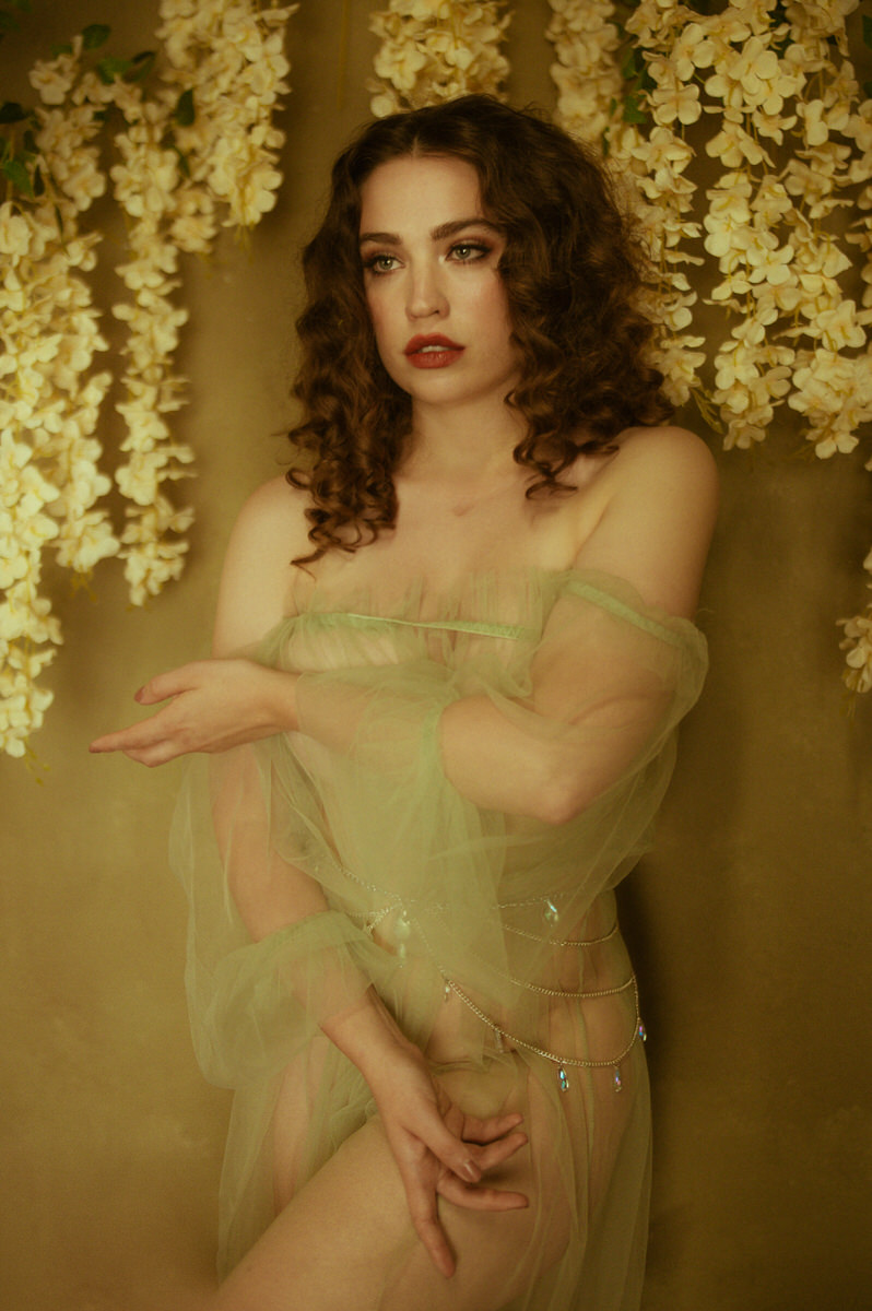 A woman in a green robe posing in front of flowers for a Dallas boudoir shoot.