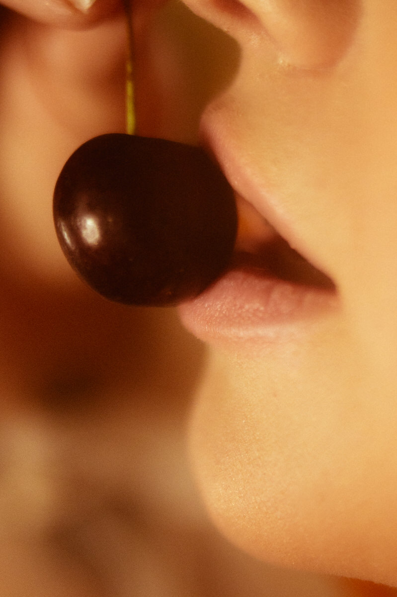 A close up of a woman eating a cherry for a boudoir photo shoot in Dallas.