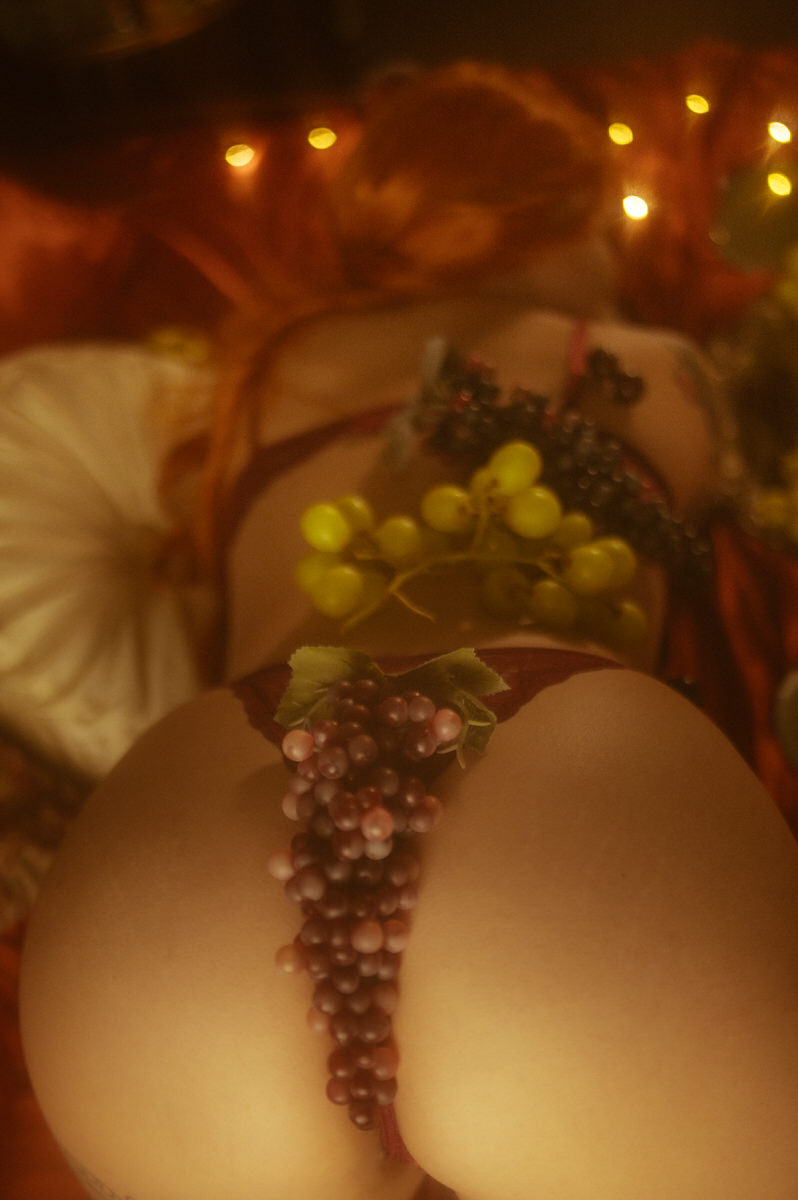 A sensual boudoir pose using grapes