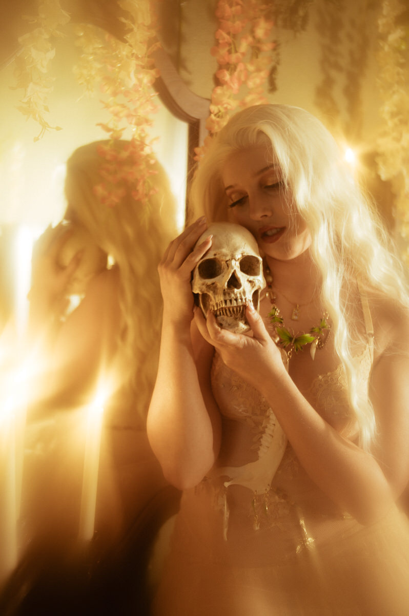 A woman holding a skull in front of a mirror for a boudoir photoshoot.