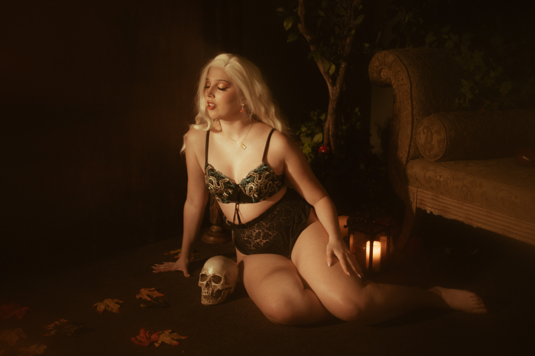 A woman posing for a Halloween themed boudoir photoshoot with a skull and candles.