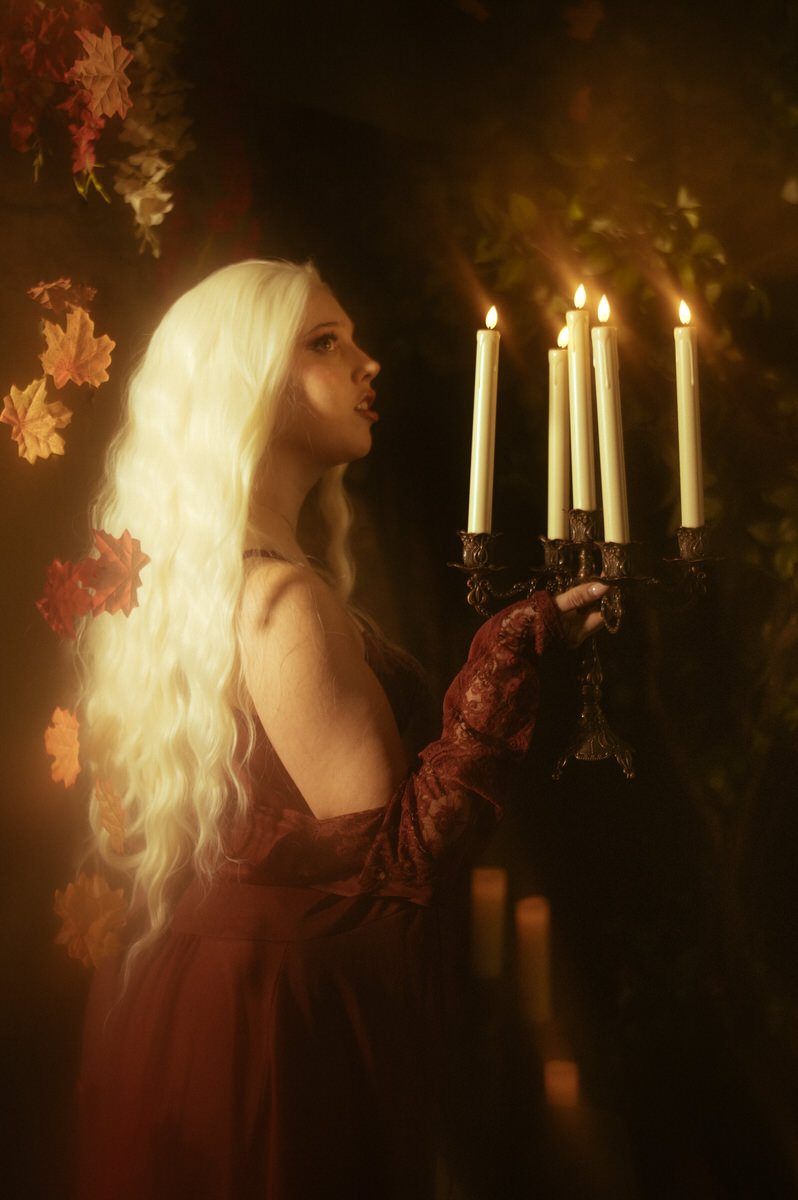 A woman in a red dress holding candles for a boudoir photoshoot.