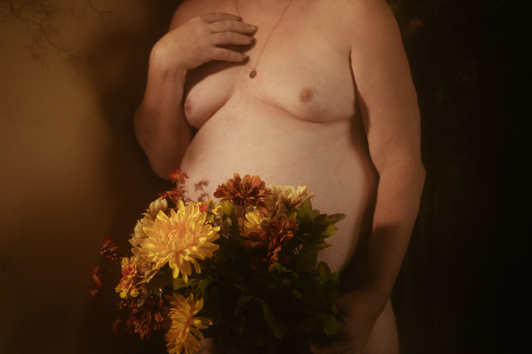 A man posing with flowers during a boudoir photoshoot.