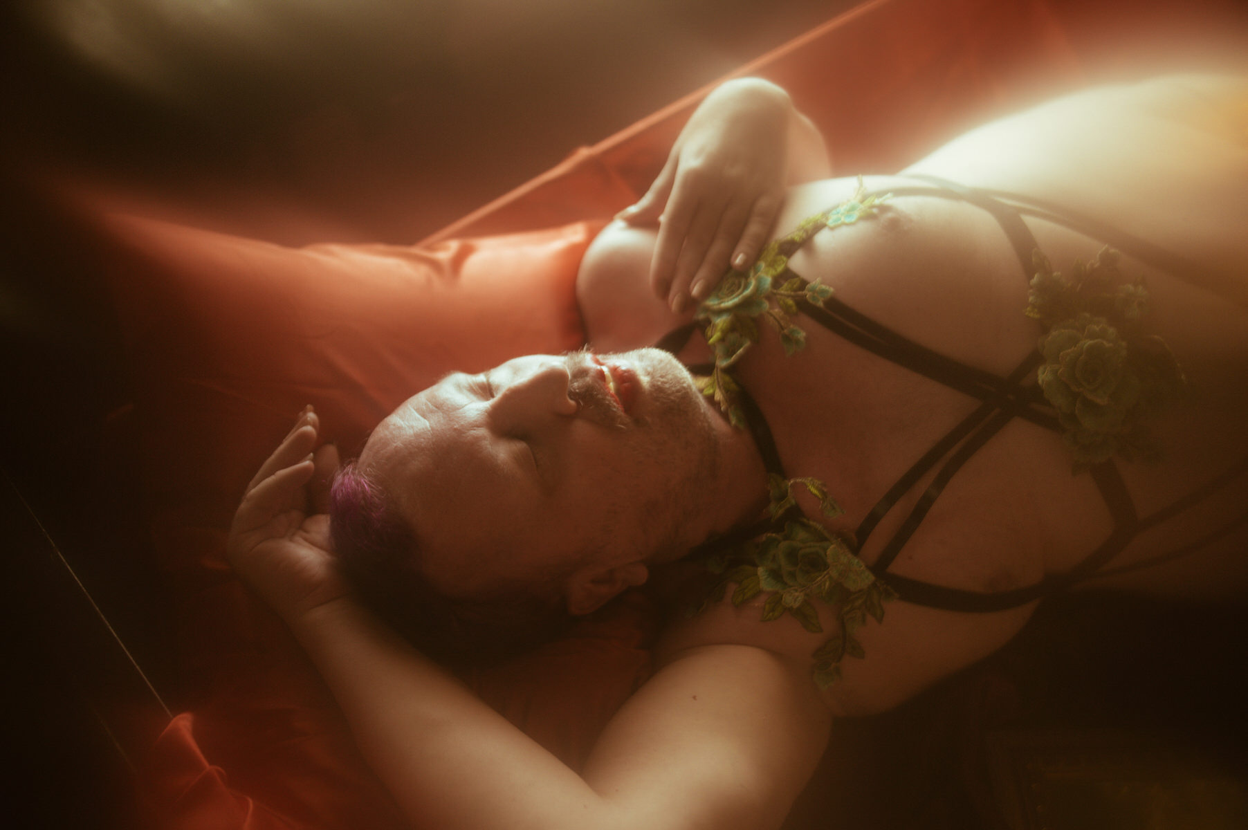 A man in lingerie laying on a bed in a Dallas boudoir studio.