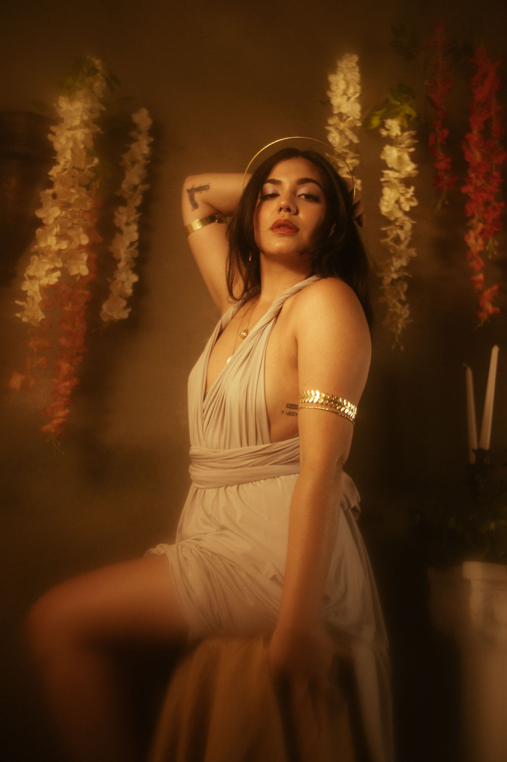 a woman in a Greek styled dress with a halo headpiece and gold arm band jewelry posing for a Libra photoshoot.