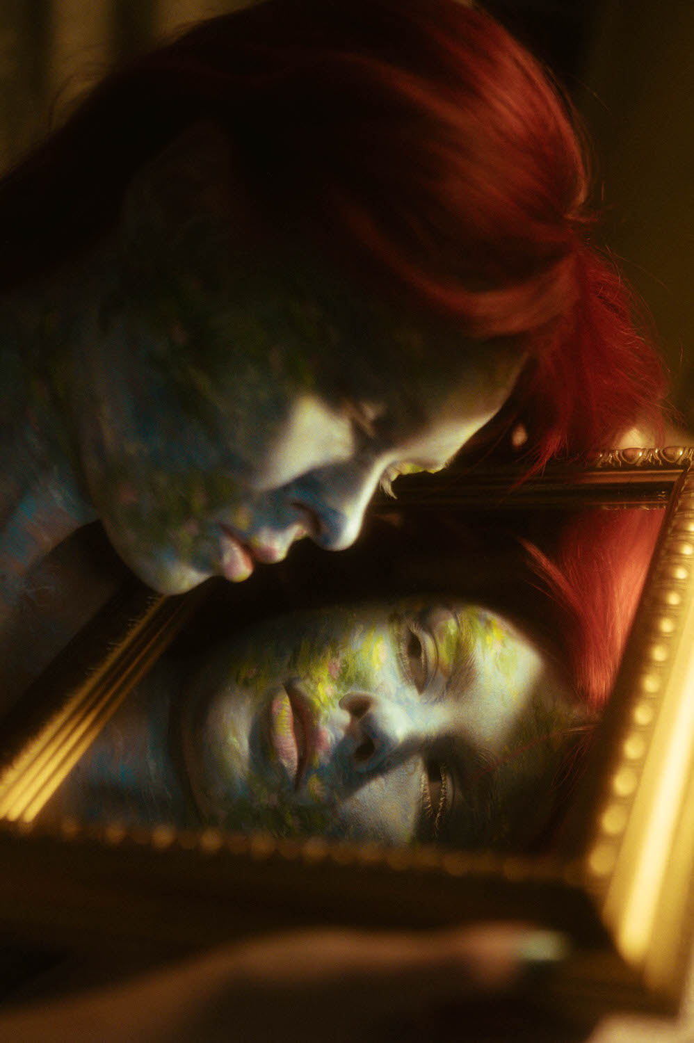 A woman with red hair and Monet-inspired blue-green face paint gazes into a mirror, reflecting their face.