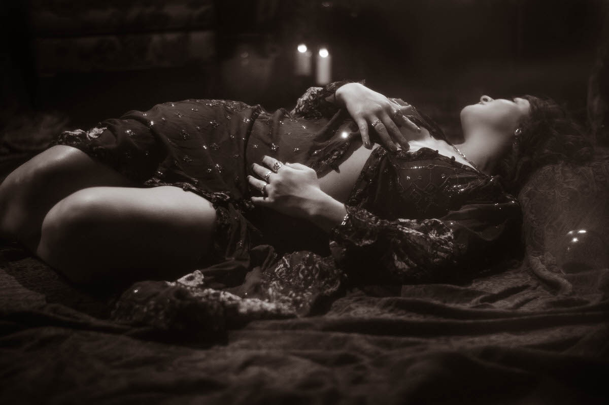 Artistic maternity boudoir portrait featuring a moody, ethereal scene with soft, dramatic lighting, highlighting the subject's form and expression.

