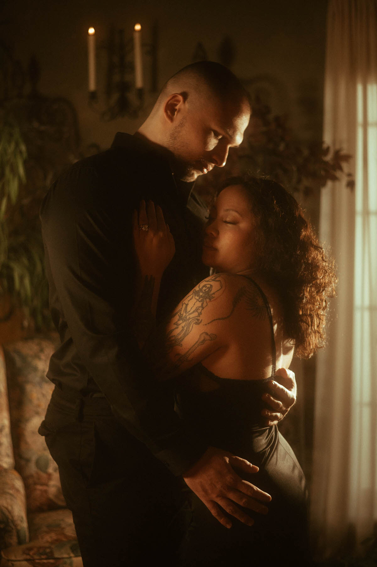 A tender moment captured during a romantic couples boudoir session, with the woman resting her head on her partner’s chest as he holds her close. The soft, moody lighting and intimate pose offer timeless couples boudoir ideas, perfect for those seeking emotional depth and sensual connection in their moody couples boudoir photoshoot.