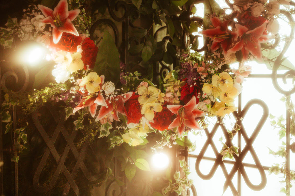 Close-up of a floral arch installation with lilies, roses, and ivy, draped over ornate wrought iron at Royal Lune Studio—perfect for spring boudoir and Dallas photography studio rentals.