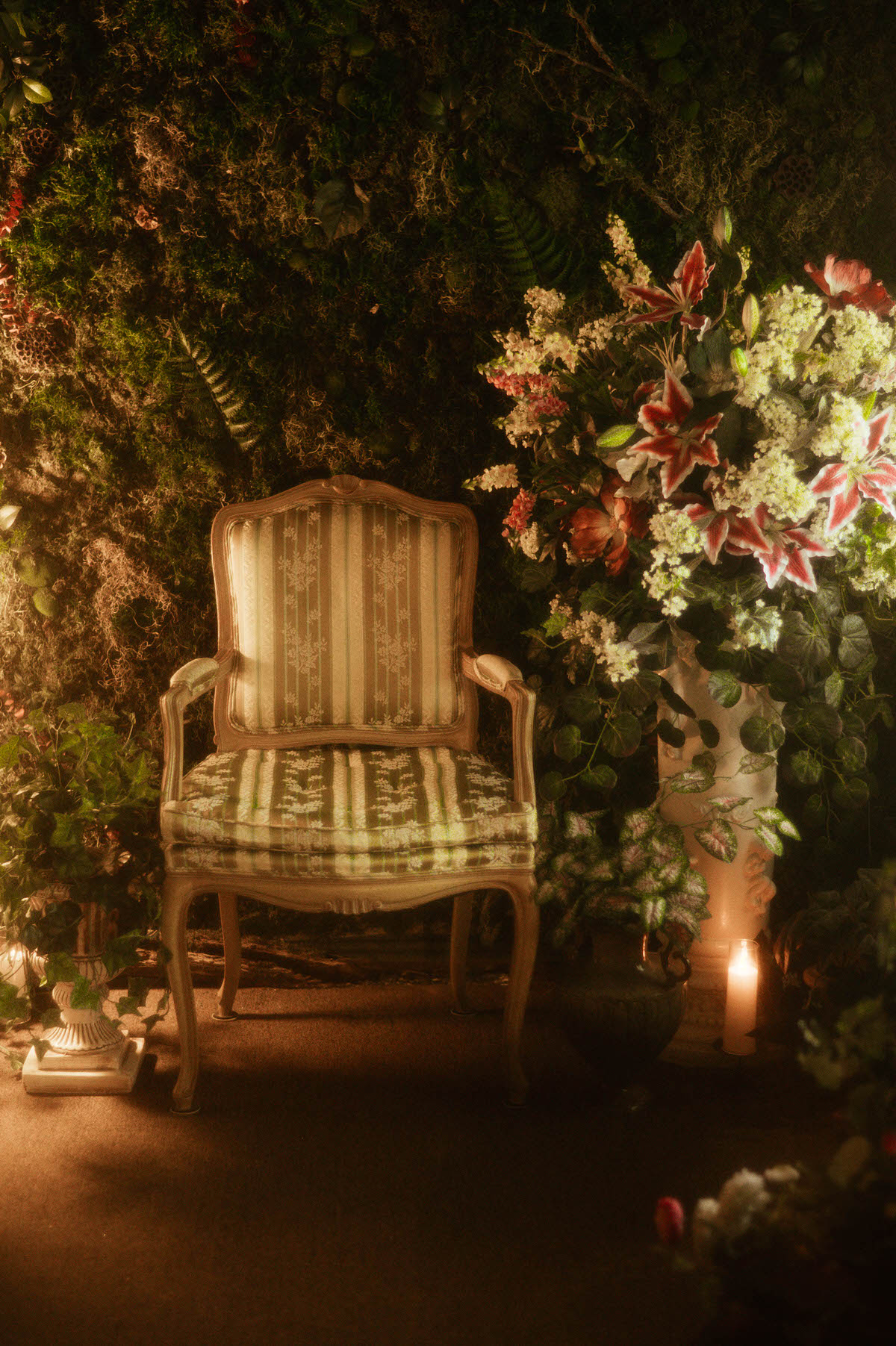 Antique French Louis XVI armchair at Royal Lune Studio framed by lush silk florals, greenery, and a moss wall, creating an elegant spring photography studio setup inside this Dallas boudoir studio and Dallas photo studio rental.