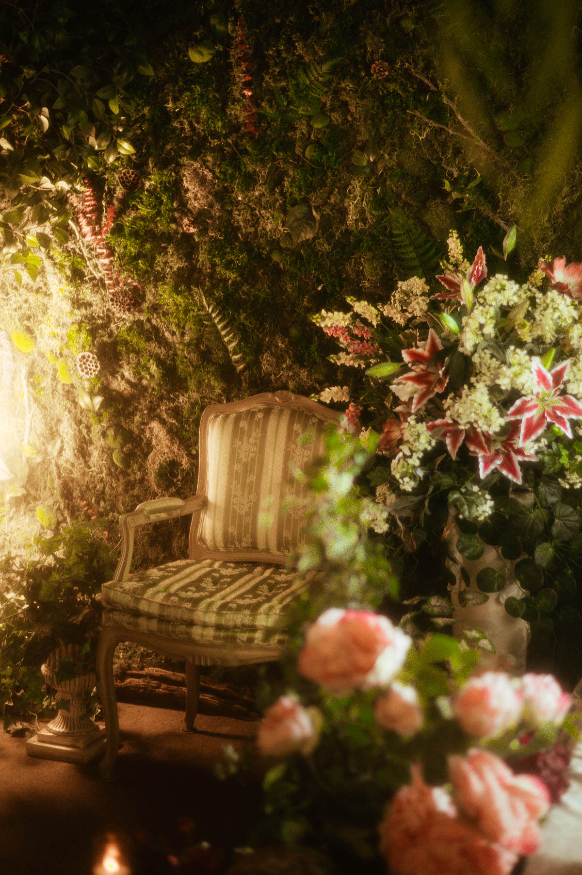 Vintage-inspired corner of Royal Lune Studio featuring a French Louis XVI armchair, cascading silk florals, and a moss-covered wall—highlighting the ethereal spring photography studio setup at this Dallas boudoir studio and Dallas photo studio rental.