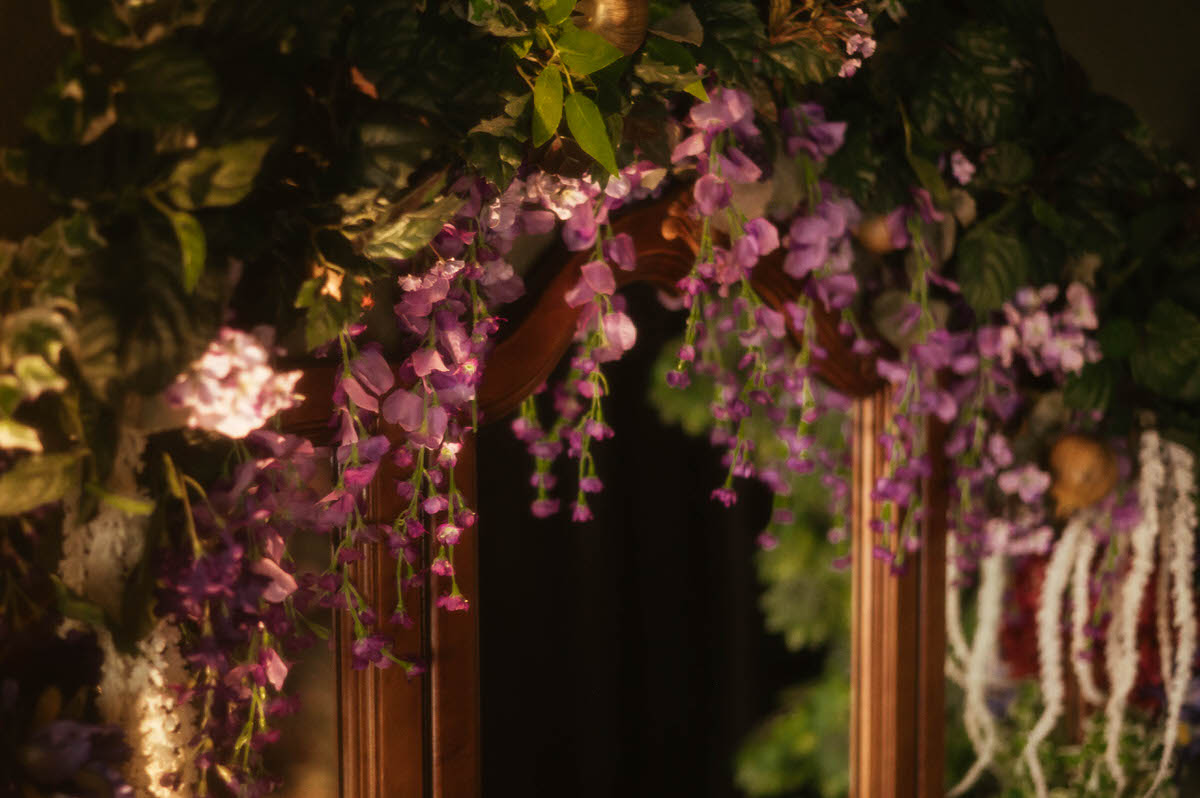 Close-up of a wooden mirror frame at Royal Lune Studio adorned with cascading silk wisteria and ivy, part of the lush floral decor in this Dallas boudoir studio’s spring photography setup.