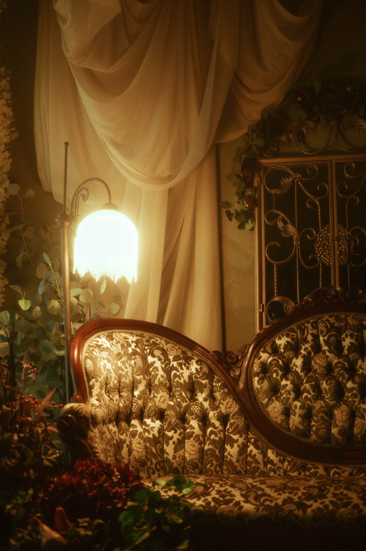 Victorian-style velvet sofa with carved wood details illuminated by a vintage fringe floor lamp, surrounded by soft cream drapery, greenery, and floral accents at Royal Lune Studio—part of the dreamy spring boudoir setup in this Dallas boudoir studio.