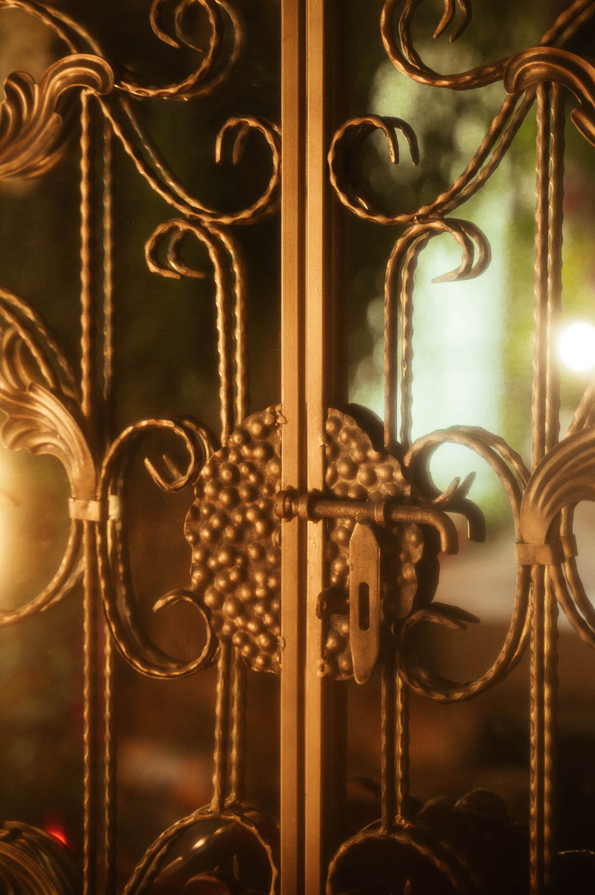 Close-up of an antique gold metal latch on a vintage scrollwork panel at Royal Lune Studio, with warm golden light casting dreamy shadows, part of the studio’s whimsical Dallas boudoir setup.