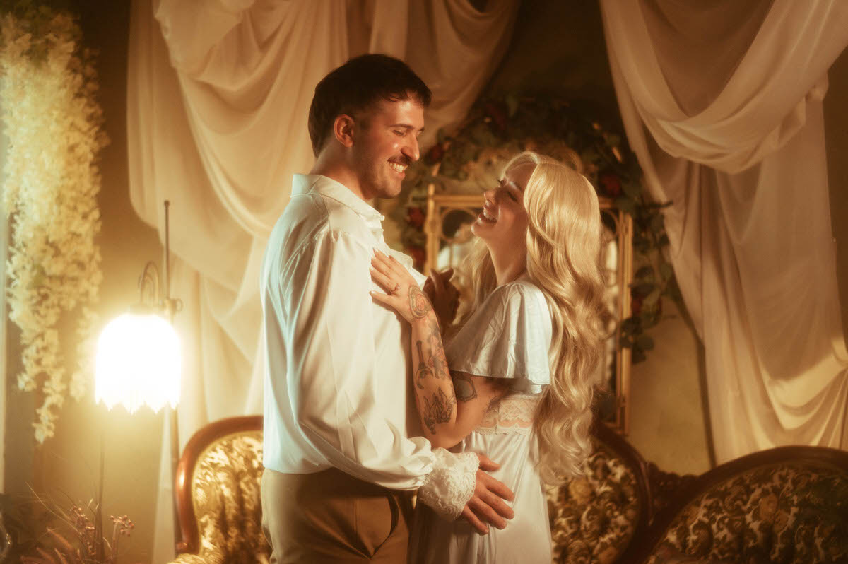 A couple laughs together in a dreamy Dallas engagement session at Royal Lune Studio, framed by vintage gold furniture, cascading ivory drapes, and soft golden lighting for a romantic, fairytale-like atmosphere.