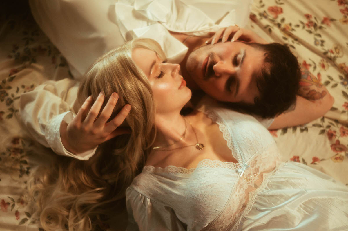 A dreamy image from an engagement session in Dallas of a couple laying and cuddling towards one another on a floral sheet. 