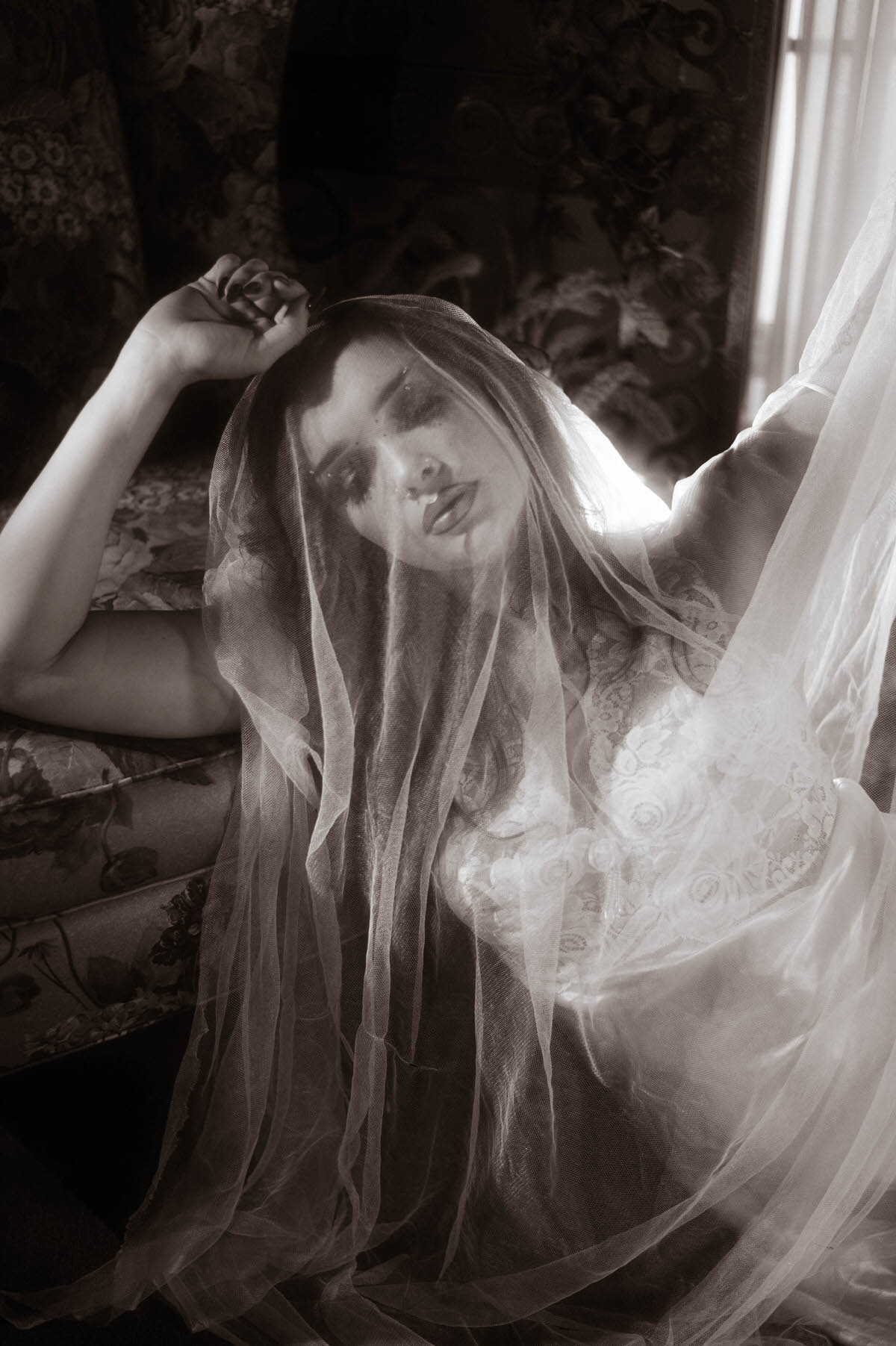 This moody fall photos black and white portrait shows a woman draped in tulle with her face tilted softly beneath the sheer fabric. Royal Lune Photo.