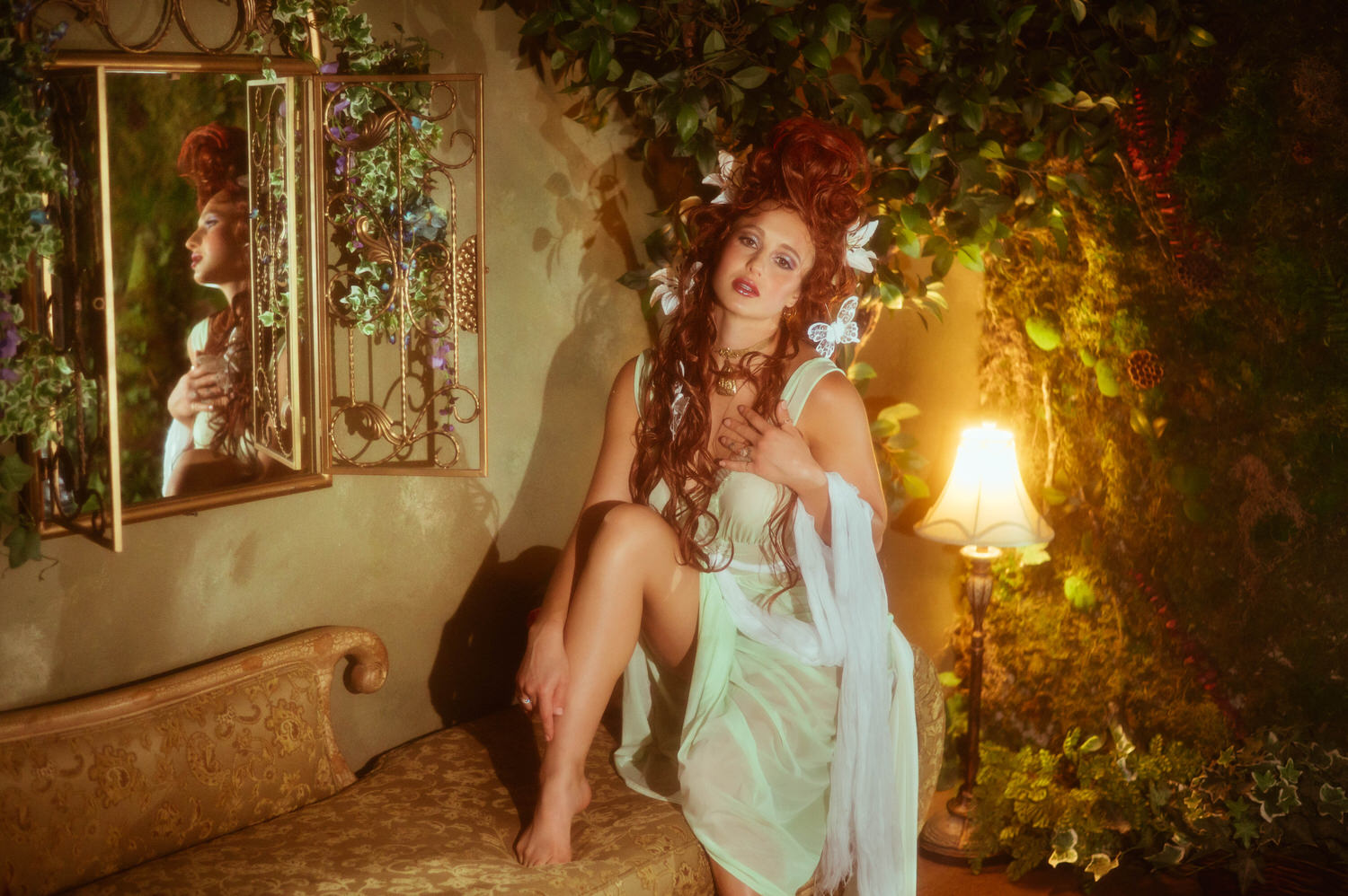 Art Nouveau photoshoot featuring a woman on a vintage chaise lounge next to a mirror and a warm lamp. Elegant fine art photography captured inside Royal Lune Studio.