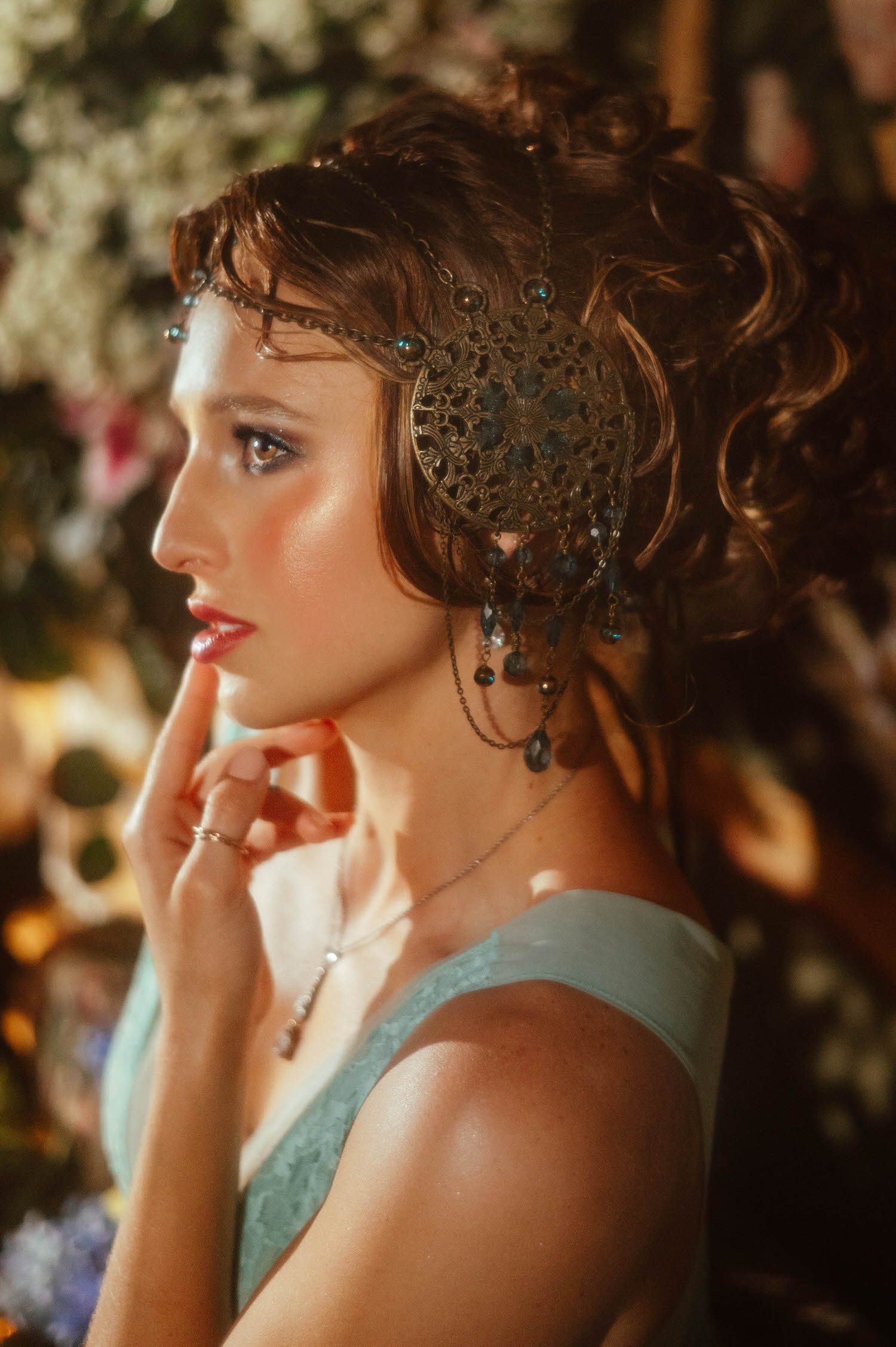 Art Nouveau inspiration beauty portrait showcasing a profile view of a woman wearing an ornate bronze headpiece with dangling beads. Photographed at Royal Lune Studio.