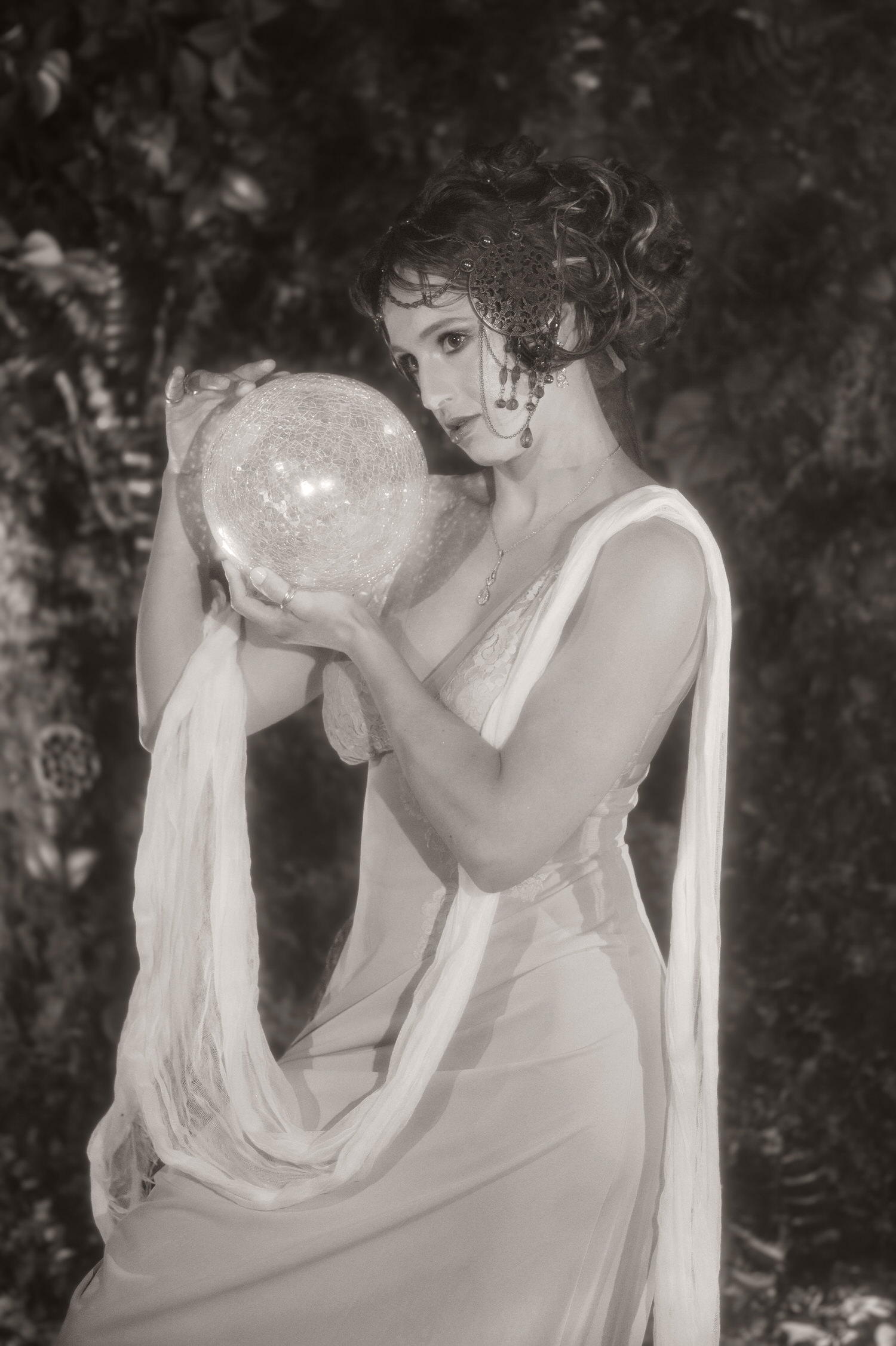 Monochrome portrait capturing Art Nouveau inspiration near Dallas. A woman with an ornate headpiece holds a bright glowing globe inside Royal Lune Studio.