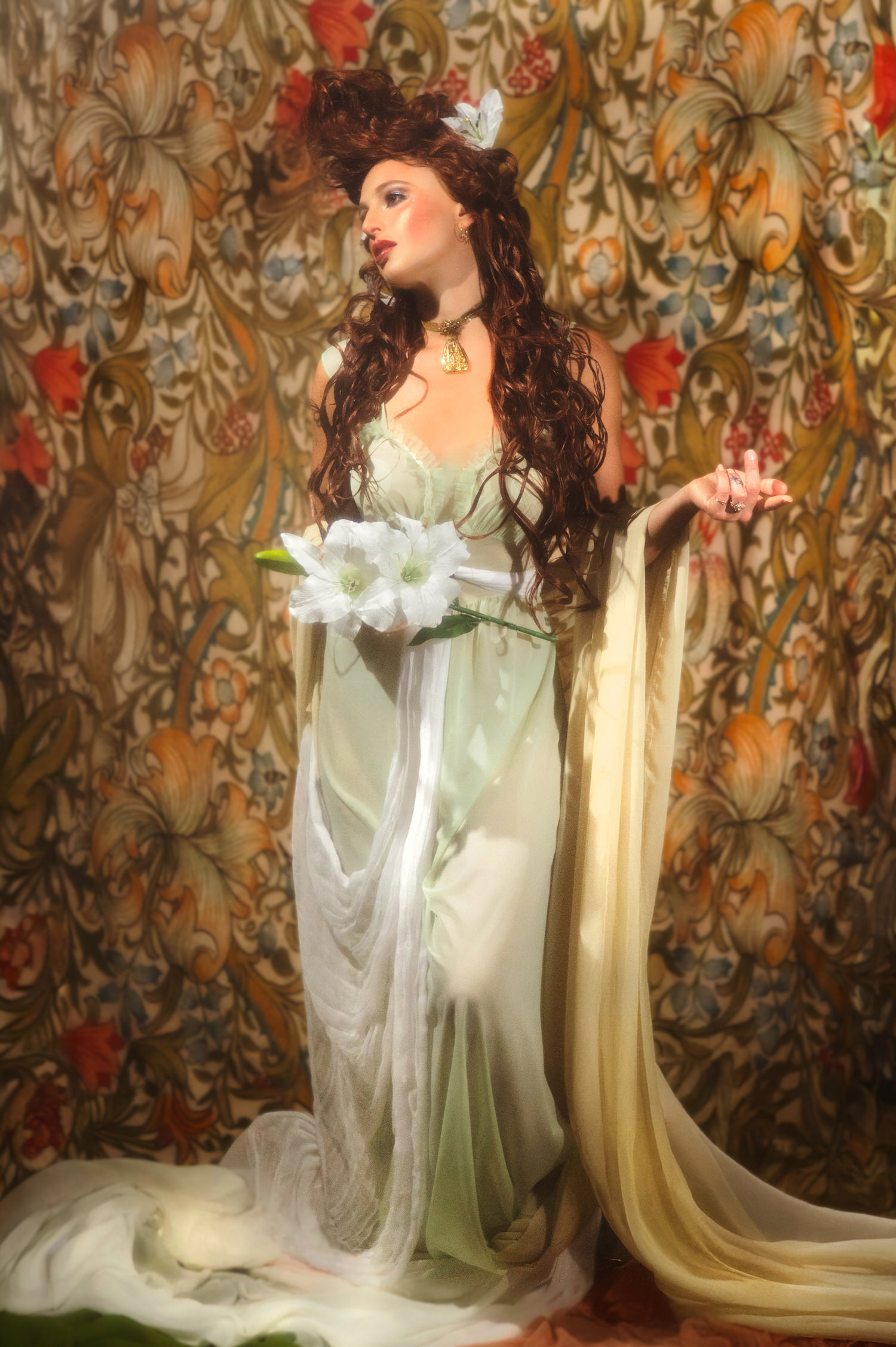 Fine art portrait in classic Art Nouveau style. A woman with an ornate updo and sage green dress poses with white flowers against a vintage botanical backdrop.