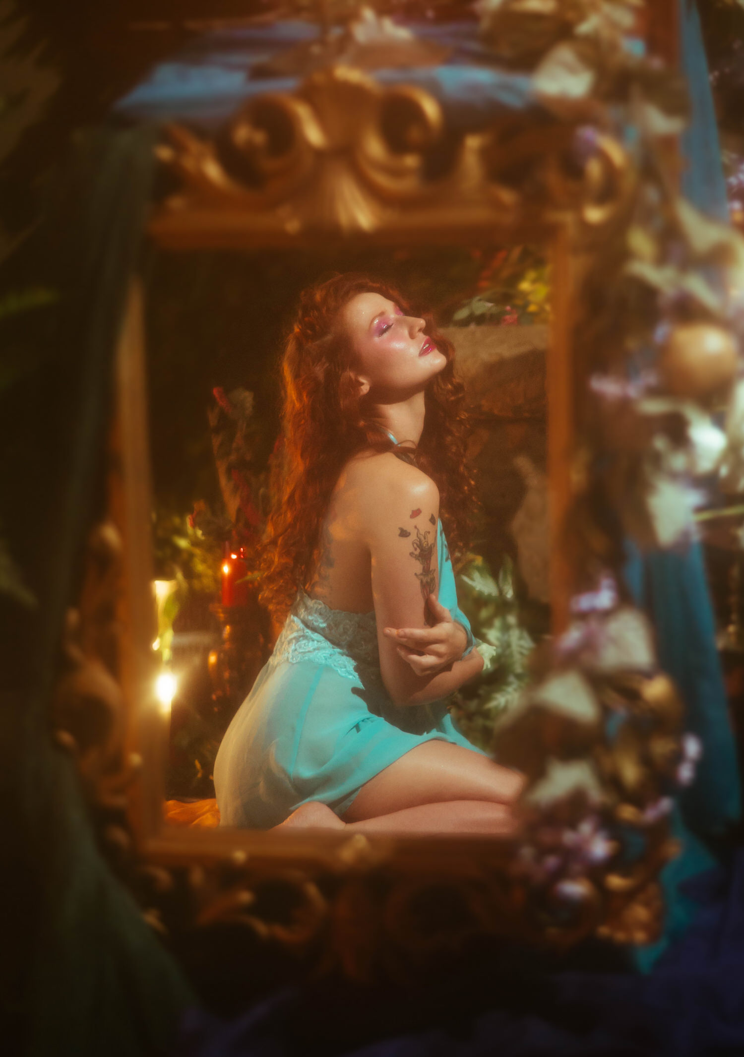 A model in a vintage lace nightgown kneels within an ornate gold mirror frame surrounded by candlelight and florals, reflecting the dreamy photography style of a Midsummer Night's Dream inspired session. This fine art portrait was captured at a Dallas area studio. Royal Lune Photo.