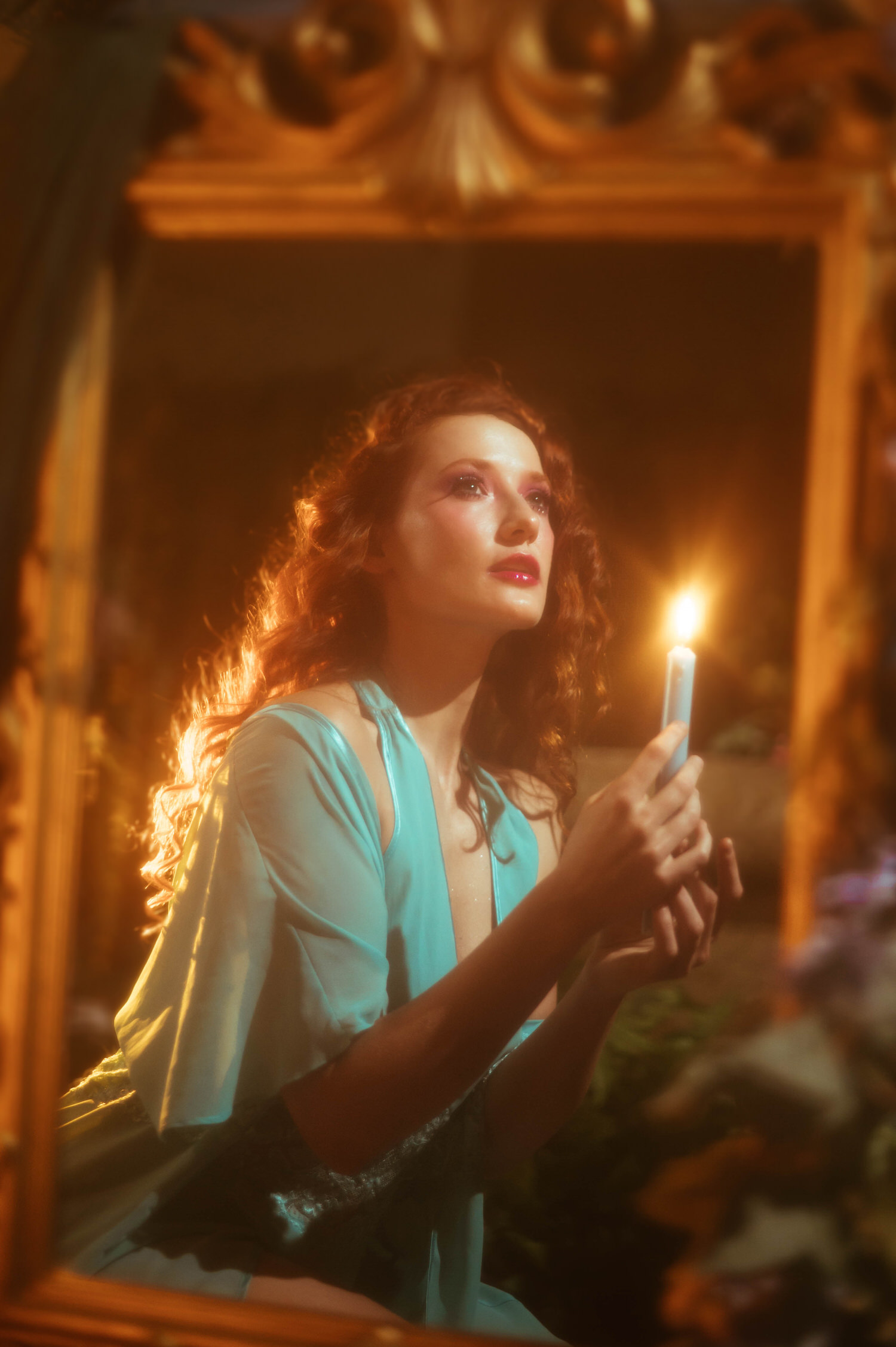 A model in a vintage lace nightgown gazes at a glowing candle within an ornate gold mirror frame, reflecting the fine art style of a Midsummer Night's Dream photoshoot. This dreamy photography studio image was captured near Dallas. Royal Lune Photo.
