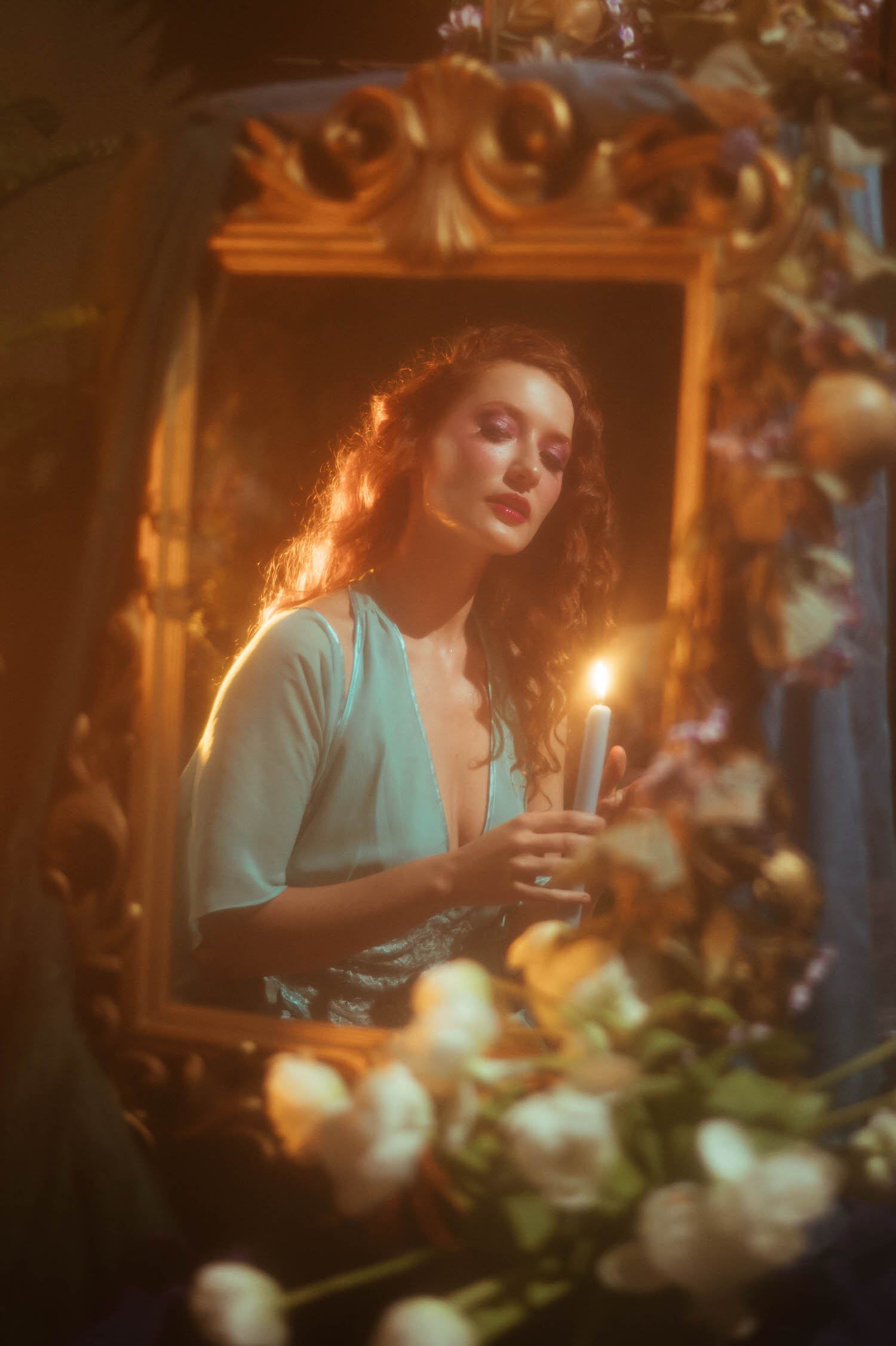 A model in a vintage lace nightgown holds a lit candle surrounded by roses within an ornate gold mirror frame, capturing the dreamy photography style of a Midsummer Night's Dream inspired session. This fine art portrait was created at a Dallas area studio. Royal Lune Photo.