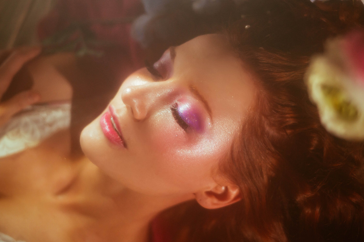 A close up beauty shot of a model with curly hair and soft pink eyeshadow, captured in warm golden light for a dreamy photography style Midsummer Night's Dream session. This fine art portrait was created at a Dallas area studio. Royal Lune Photo.