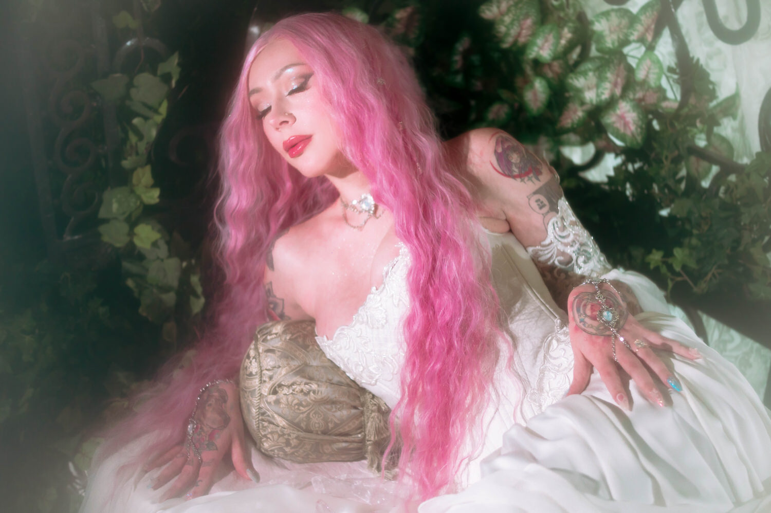 Close portrait of bride in fantasy wedding photography setting, wearing an embroidered corset gown with flowing chiffon sleeves and layered bridal jewelry.